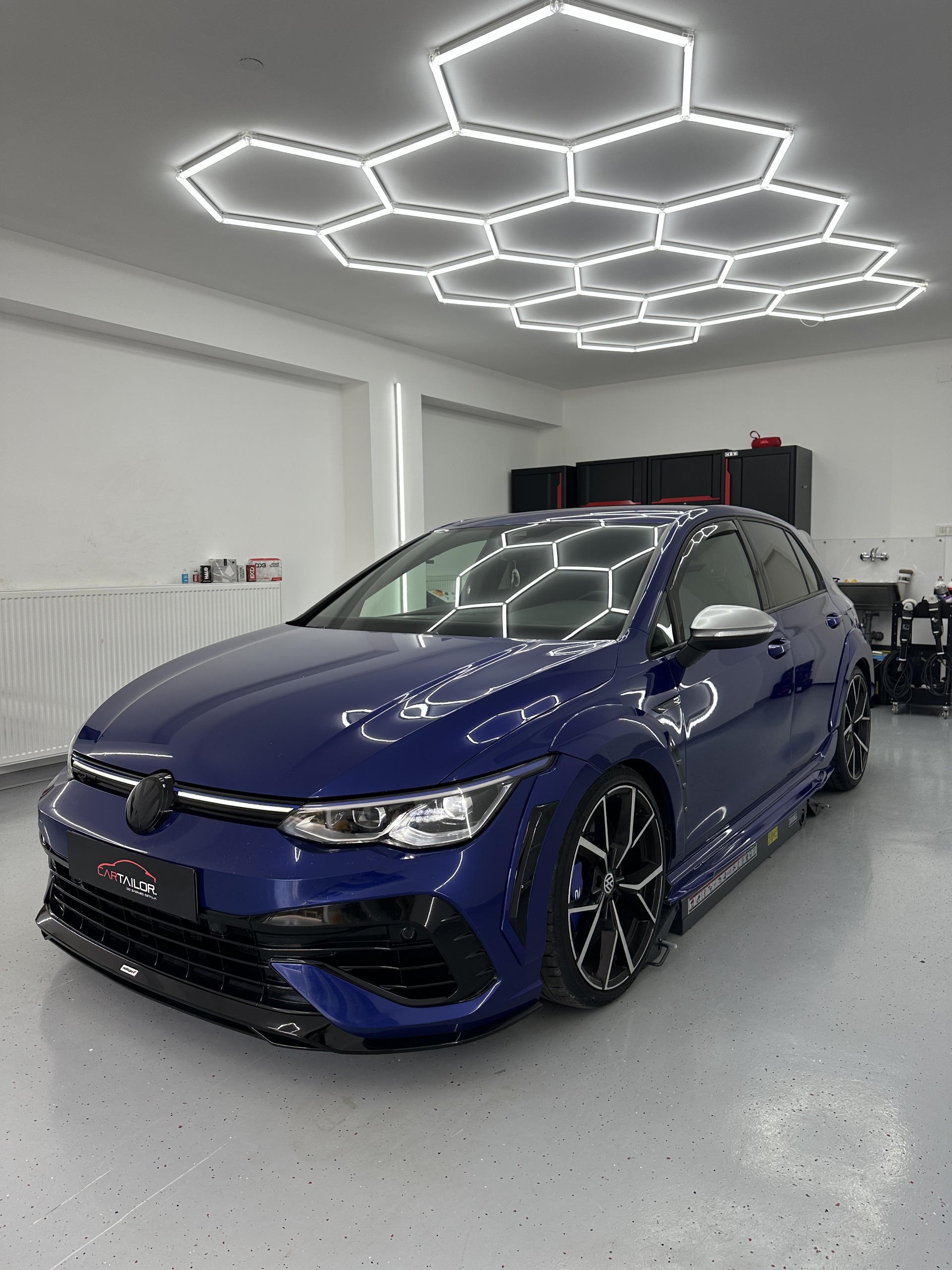 Plavi Golf R sprijeda u Car Tailor boksu, s odrazom rasvjete na haubi.